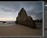Scogliera imponente su una spiaggia al tramonto, con onde mosse. L'aggiornamento Lightroom sta migliorando i dettagli dell'immagine.