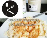 Milchreis eingekocht in Gläsern, bereit zum Genießen. Ein Löffel, Gabel und Messer bilden ein K im Kreis.