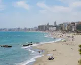 Sonniger Benalmadena Strand mit vielen Menschen, bunten Sonnenschirmen und dem türkisfarbenen Meer.