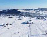 Zimowy krajobraz z wyciągiem narciarskim Horników Wierch u Goryla. Śnieg pokrywa pola i dachy domów, tworząc malowniczy widok.