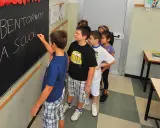 Schulkinder stehen vor einer Tafel mit der Aufschrift "Bentornati a scuola". Sie warten gespannt, wie viele Schultage ein Jahr hat.