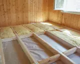 Travaux d'isolation du sol d'une maison ancienne : pose d'isolant minéral dans une structure en bois.