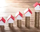 Cinq maisons miniatures sur des piles de pièces, symbolisant une augmentation du loyer sur 3 ans.