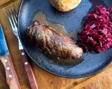 Herzhafte Rouladen im Dutch Oven zubereitet, serviert mit Rotkohl und Klößen auf einem rustikalen Teller.