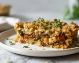 Tranche de crumble de légumes, dorée et croustillante, garnie de thym frais. Un délice végétarien réconfortant.