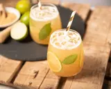 Erfrischender cocktail mit braunem rum, Limette und Minze, serviert mit Eis und einem gestreiften Strohhalm.