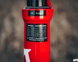 Czerwiony amortyzator Rock Shox z naklejką zawierającą tabelę ciśnień i ustawień powrotu dla różnych wag rowerzysty.