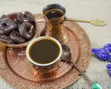 Ein traditionelles Mokkakännchen mit starkem Kaffee, dazu Schokoladenkekse und blaue Blumen. Was ist Mokka? Ein Genuss für die Sinne.