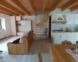 Come arredare una taverna: cucina bianca, divano in legno, scala a vista e soffitto a travi.
