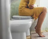 Person med magont sitter på toaletten. Kanske en dålig kombination av loperamid och alkohol?