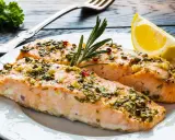 Två saftiga laxfiléer med en härlig pesto-topping, garnerade med rosmarin och en citronklyfta.