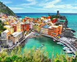 Vernazza, una delle Cinque Terre, con case colorate a picco sul mare turchese e un porticciolo pieno di barche.