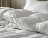 Biała, puszysta kołdra i poduszki na hotelowym łóżku.