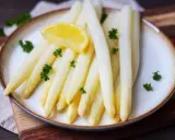 Frischer weißer Spargel, perfekt gekocht, garniert mit Petersilie und einer Zitronenspalte auf einem Teller. Ein Genuss, der Lust auf mehr macht.