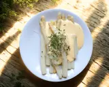 Vitt sparris på en tallrik med en krämig sås och färska örter. Perfekt att koka sparris till en lätt och god måltid.
