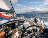 Voile blanche et rouge gonflée par le vent, le barreur guide le voilier. Un aperçu du lexique marin en action.