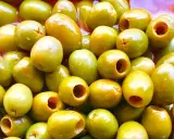 Un primer plano de muchas aceitunas verdes, algunas deshuesadas, listas para ser parte de las clases de aceitunas para comer.