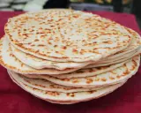 Una pila di piadine dorate, appena sfornate, con macchie di cottura che invitano a gustare questo classico della cucina romagnola.