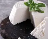 Świeża ricotta z bazylią na ciemnej desce.
