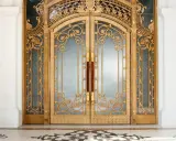 Prunkvolle goldene Doppeltür im **Art déco Baustil** mit filigranen Verzierungen und Marmorboden.