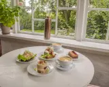 Fika på ett mysigt cafe i Skåne med smörgåsar, tårtor och kaffe.