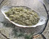 Pyszna kapusta zasmażana z koperkiem, podana w ozdobnej misie na tle drewnianej tekstury.