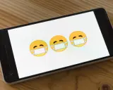 Trzy emoji w maseczkach na ekranie smartfona. Dowiedz się, jak usunąć wirusy z iPhone.