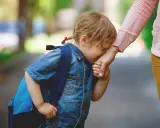 Niña con mochila azul llora y se aferra a la mano de su madre. Parece que mi hija no quiere ir al colegio.