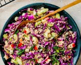 En färgglad couscous sallad med rödkål, äpple och mynta. En gyllene sked vilar i den fräscha rätten.