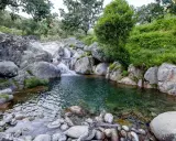 Unas idílicas piscinas naturales en Valladolid, con cascadas y rocas, rodeadas de vegetación exuberante.