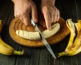 Dłonie kroją banana na desce. To świetny pomysł, co jeść na skurcze nóg, bo banany są bogate w potas.