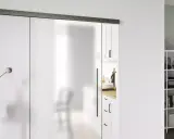 Puerta corredera de cristal esmerilado con tirador negro. Una guía superior negra y un riel inferior negro son clave para como poner una puerta así.