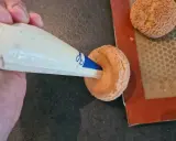Garnissage d'une pâte à choux profiterole avec une crème onctueuse à l'aide d'une poche à douille.