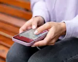 Dłonie kobiety obsługują smartfon, który wyświetla listę e-maili. To przykład interakcji, która może wykorzystywać haptykę – co to za technologia?