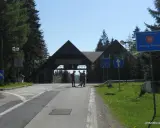 Przejście graniczne na Pilsku. Znaki drogowe i budynek z napisem "Wyciągi Narciarskie". Szlaki górskie w tle.