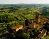 Un borgo medievale con una torre svetta tra le verdi colline pisane, un paesaggio da cartolina.