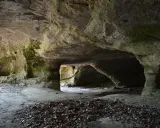 L'interno di una grotta scavata nella roccia, con nicchie e passaggi che ricordano Vitozza, la città perduta.