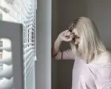 Mujer rubia con la mano en la frente, mirando hacia abajo, con un aire de melancolía que evoca el síndrome de Wendy.