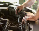 Mecánico revisa el motor de un coche. El sonido de aire al acelerar el coche podría ser un problema.