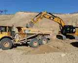 Excavadora CAT cargando volquete Volvo en obra de movimiento de tierras.