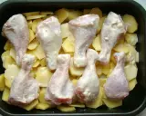 Osiem pałek kurczaka w sosie, ułożonych na plastrach ziemniaków w brytfannie. Idealne do pieczenia, by uzyskać chrupiące pałki z kurczaka w piekarniku.
