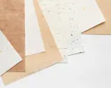 Różne rodzaje papieru, od gładkich po z widocznymi włóknami i złotymi płatkami.