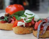 Drei italienische Bruschetta mit Tomaten, Mozzarella und Sardellen auf geröstetem Brot.