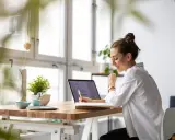 Uśmiechnięta kobieta pracuje przy laptopie, planując swój **ecommerce dropshipping**. Sukces w biznesie online!