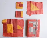 Kilka fragmentów tkanin w odcieniach koralu i żółci, tworzących wzory geometryczne. To jest właśnie patchwork – sztuka łączenia skrawków materiału.