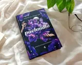 Powieść Patricka Süskinda "Pachnidło" na tle białej tkaniny, obok okularów i innej książki.