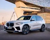 BMW iX5 Hydrogen, ein Vorreiter unter den BMW Elektro Modellen, mit futuristischer Architektur im Hintergrund.