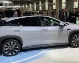 En vit BYD-bil visas på en mässa. Människor tittar på bilen, kanske potentiella byd återförsäljare.