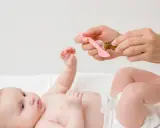 Mama podaje dziecku krople na wzdęty brzuch u noworodka.