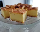 Pyszny sernik na kruchym spodzie, pokrojony na kwadraty, prezentuje się apetycznie na szklanej paterze.